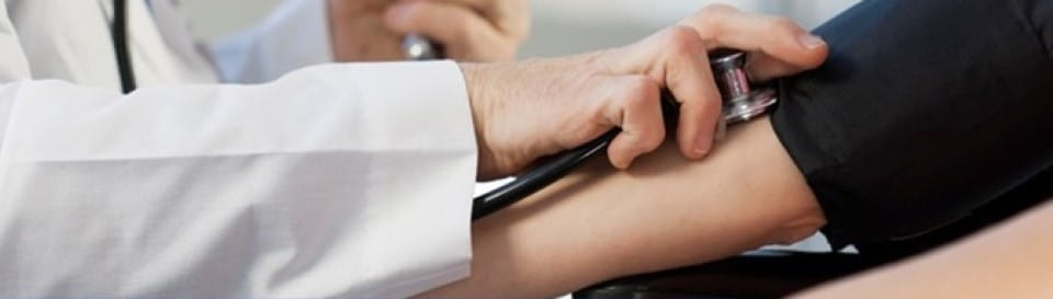 Arbeitsmedizinische Vorsorge: Ein Arzt hält ein Stethoskop am Arm eines Patienten